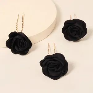 Three-piece black fabric rose hair pins with gold wave U-shaped clips on a beige background