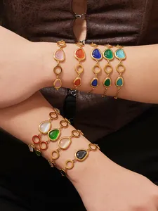 Detail von 18k vergoldeten Armbändern mit ovalen Katzenaugensteinen am Handgelenk