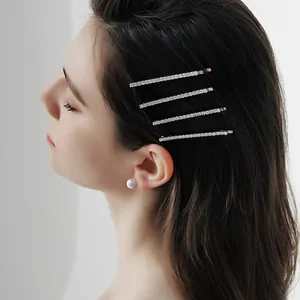 Élégant ensemble de quatre barrettes en métal argenté avec strass blancs sur un mannequin