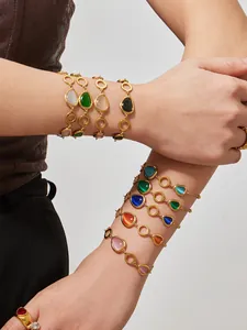 Detailansicht mehrlagiger 18k vergoldeter Armbänder mit bunten ovalen Katzenaugen-Steinen