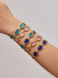 Nahaufnahme von vier facettierten Katzenaugenstein-Armbändern mit goldenen Ketten am Handgelenk