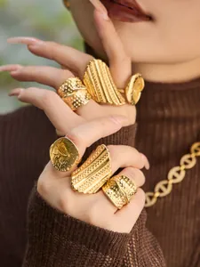 Nahaufnahme von gehämmerten Goldringen und einer klobigen Kette an der Hand
