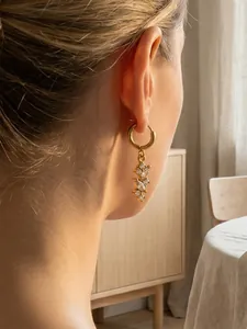 Dettaglio degli orecchini a nappa placcati in oro con pietre di zircone indossati da una modella