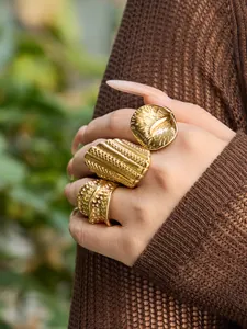 Nahaufnahme von drei klobigen 18k vergoldeten Edelstahlringen mit Hammerschlag-Optik am Model