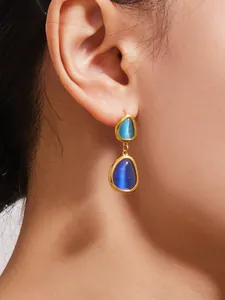 Nahaufnahme von vergoldeten Ohrringen mit blauem Katzenaugenstein aus Edelstahl-Schmuck