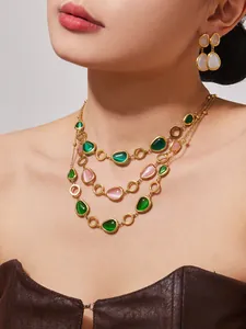 Detail einer mehrlagigen Goldkette mit Katzenaugensteinen und passenden Ohrringen am Model