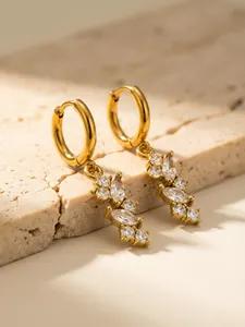 Dettaglio degli orecchini pendenti dorati con zircone marquise su pietra naturale