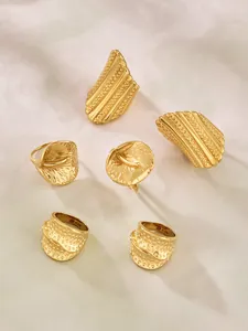 Makroaufnahme von vergoldetem Edelstahlschmuck mit Hammerschlagstruktur und ACIER-Gravur