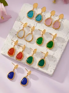 Nahaufnahme von Tropfen-Ohrringen mit Katzenaugenstein in vielen Farben und Gold