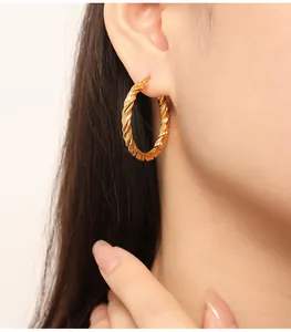 Close-up of golden twisted hoop earring worn on ear with high quality metallic detail