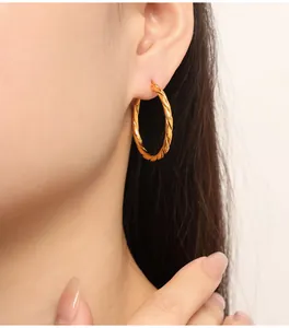 Close-up of golden twisted rope hoop earrings worn on model for a modern look