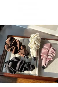 Detail of four pleated satin banana hair clips in brown beige pink and black