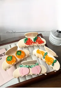 Detail view of fruit-shaped hair claws including strawberry, persimmon, mango, and peach