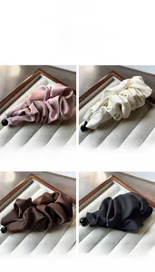 Detailed view of satin pleated banana hair clips in pink, cream, brown and black colors