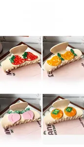 Detail showing four acetate fruit hair claws in cream colors: strawberry, mango, peach, and persimmon