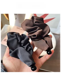 Detailed macro view of large pleated satin bow banana clips in black and brown finishes