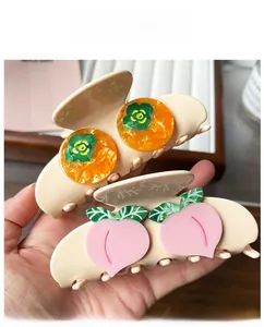 Detail of acetate hair claws featuring 3D persimmon and peach fruit designs