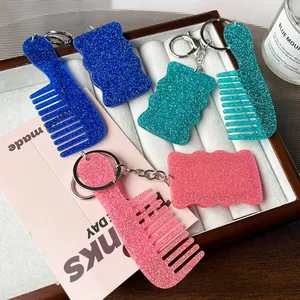 Glitter acrylic heart mirror and comb keychains displayed on a white jewelry tray