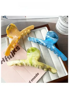 Gros plan de pinces à cheveux marbrées en ambre, bleu et vert sur un plateau déco