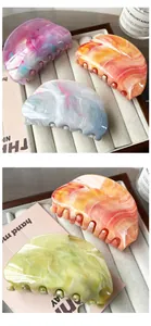 Close-up of marble acetate hair claw clips with elegant ink-wash pattern on soft display