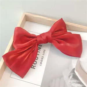 Gros plan d'une pince à cheveux nœud en satin rouge sur un fond en bois épuré