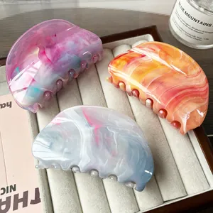 Three-piece set of large marble pattern hair claws in gradient acetate on a velvet tray