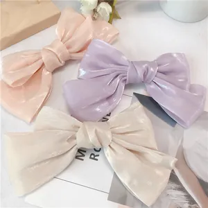 Détail de trois barrettes à nœud nacré en rose, violet et blanc crème de haute qualité