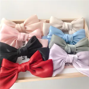 Lot de barrettes à nœuds en satin de plusieurs couleurs présentées sur un plateau