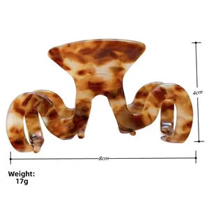 Détail d'une pince à cheveux en forme de M effet écaille montrant les dimensions 8cm par 4cm