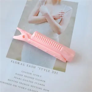 Pink hair root volumizing clip with comb teeth detail on a stylish magazine background