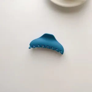 Close-up of a matte blue hair claw clip on a minimalist white ceramic background