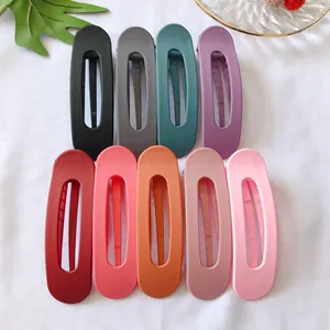 Dettaglio di nove mollette per capelli rettangolari opache in vari colori su tessuto