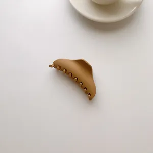 Macro shot of mocha brown matte hair claw clip with wavy edges on minimalist background