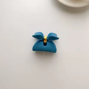 Detail of Klein blue matte hair claw clip with golden metal fastener and bow shape