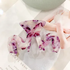 Détail de la pince à cheveux en acétate en M avec motif marbre violet sur magazine