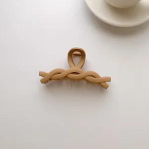 Close-up of matte cream hair claw clip with twisted woven design and metal spring