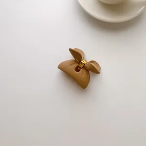 Detailed macro view of a matte camel bow shark hair clip with a sturdy gold metal spring