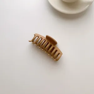 Detail view of the matte khaki shark hair claw clip with a minimalist geometric design
