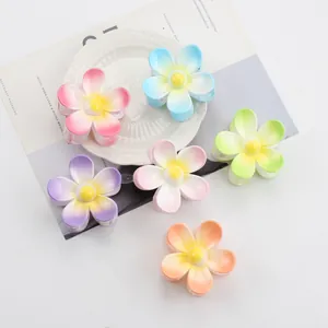 Elegante Blumen-Haarklammern in sechs Pastellfarben auf einem weißen Dekoteller