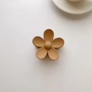 Macro shot of a matte caramel-colored five-petal flower hair claw on a beige surface