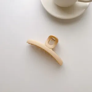 Detail of a large matte cream hair claw clip with a secure grip on a minimalist background