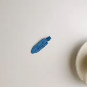 Detail of blue matte hair clip with embossed UANODIAM lettering on minimalist background
