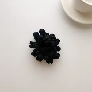 Detail of a fluffy black plush hair scrunchie made of soft chenille fabric for winter