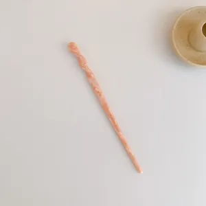 Detail einer hellrosa marmorierten Acetat-Haarnadel mit gedrehtem Oberteil-Design