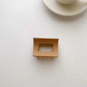 Macro shot of milk tea color matte hair claw clip with a hollow rectangular geometric design