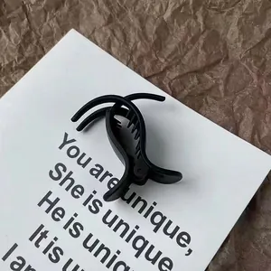 Detailansicht der mattschwarzen Haarklammer auf minimalistischem strukturiertem Hintergrund