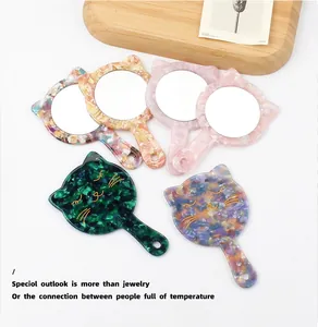 Detail of cat-shaped acetate hand mirror with floral pattern and marble texture