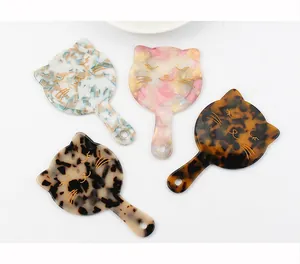 Detailed view of cat-shaped acetate hand mirrors with artistic floral patterns and gold lines