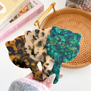 Three acetate cat-shaped hand mirrors in tortoiseshell, leopard, and green marble patterns