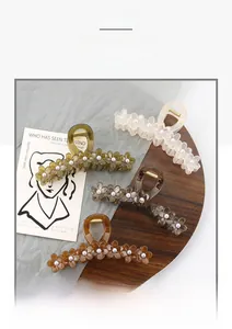 Detail of four floral hair claws with pearl centers in jelly colors on a wooden tray